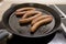 French merguez sausages frying in a oil in a pan