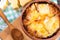 French onion gratin soup in a clay pot, authentic recipe, wooden spoon on a cutting board on an old rustic table, close-up