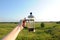 French press in hand on the backdrop of summer sunny suburban landscape with blue sky and greenery