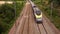 French railway blue train moving along rail road. Passenger bullet train passes on railway view from above, contryside