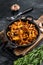 French roasted chanterelle mushrooms with onions and thyme in a pan. Black background. Top view