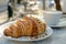 French style breakfast croissant with nuts, cappuccino in a summer cafe outdoor setting