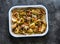 French style chicken with new potatoes, carrots, lemon and thyme in baking tray on a dark background, top view