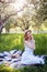 French style romantic picnic setting. Woman in cotton dress and hat with glass of wine, strawberries, croissants, brie cheese, sun