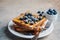 French toast with blueberries, pecan and maple syrup for breakfast on white plate