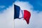 French tricolor flag fluttering with strong wind and blue sky