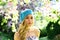 French woman. Girl wears dress and blue beret walks in blossom park on sunny spring day. Young woman enjoy nature.