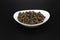 Fresh allspice in a dish on a black background