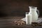 Fresh almond milk in glass and pitcher on dark wooden table. Rustic style