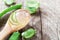 Fresh aloe vera gel in spoon and green aloe vera leaf on wooden table.