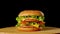 Fresh appetizing hamburger rotating on black background. Seamless loopable shot, 4k.