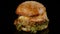 Fresh appetizing hamburger rotating on black background. Seamless loopable shot, 4k