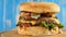 Fresh appetizing hamburger rotating on blue background.