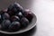 Fresh appetizing plums in a gray bowl, summer concept, copy space