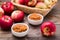Fresh applesauce in bowls and red apples on a wooden table