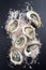 Fresh Australian Sydney rock oysters with garlic and salt on a black design board