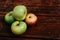 Fresh autumn Apple harvest on the kitchen countertop. Four fresh apples lie on a wooden table. A textured mahogany wood background