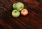 Fresh autumn Apple harvest on the kitchen countertop. Four fresh apples lie on a wooden table. A textured mahogany wood background
