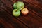 Fresh autumn Apple harvest on the kitchen countertop. Four fresh apples lie on a wooden table. A textured mahogany wood background