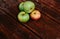 Fresh autumn Apple harvest on the kitchen countertop. Four fresh apples lie on a wooden table. A textured mahogany wood background