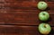 Fresh autumn Apple harvest on the kitchen countertop. Three fresh green apples lie in a row on a wooden table. A textured mahogany