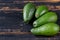 Fresh avocados on the dark wooden background with free copy space. Raw ingredients for veggie salad or diet dish