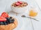 Fresh bagel with berries, oatmeal and honey on a white background. French summer breakfast