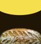 Fresh baked bread on dark brown and illuminating yellow semicircle background. Natural bakery products. Bread making advertising.