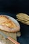 Fresh baked bread on a wooden cutting board burlap with a bunch of wheat on burlap on a black background. Rustic style.