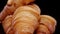 Fresh baked croissants close up macro view. French croissants rotating on a black background.