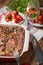 Fresh Baked Lasagne in Red Dish with Black Olives Tomatoes and Chilli on Wooden Table