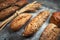 Fresh bakery food. Crusty loaves of mixed breads and buns and ears of wheat on rustic table background.