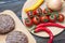 Fresh beaf burgers on cutting board with tomato, pepper and onion.