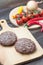 Fresh beaf burgers on cutting board with tomato, pepper and onion.