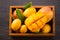 Fresh and beautiful mango fruit set in a wooden box with sliced diced mango chunks on a dark wooden background, copy space