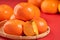 Fresh beautiful sliced sweet persimmon kaki isolated on red table background and bamboo sieve, Chinese lunar new year design