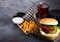 Fresh beef burger with sauce and vegetables and glass of cola soft drink with potato chips fries on stone kitchen table background