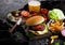 Fresh beef burger with sauce and vegetables and glass of craft lager beer with potato chips fries on stone kitchen table