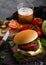 Fresh beef burger with sauce and vegetables and glass of craft lager beer with potato chips fries on stone kitchen table backgroun