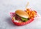 Fresh beef burger with sauce and vegetables with potato chips fries in red serving basket on stone kitchen table background. Fast