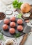 Fresh beef raw meatballs on stone board with pepper, salt and garlic on light background with dill,parsley and dill