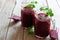 Fresh beet juice in mason jars with beets over rustic wood