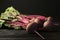 Fresh beets with leaves on dark wooden table against black background