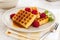 Fresh belgian waffles with syrup and raspberries