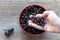 Fresh Berries Of Black Hawthorn (Crataegus nigra) In Male Hands In A Bowl On A Wooden Table Closeup