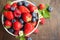 Fresh berries in withe bowl on rustic wooden Background