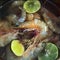 Fresh big shrimps in metal pot with limes in water