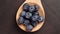 Fresh bilberry berries in a wooden spoon on a brown background. Ripe blueberries.