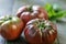 Fresh Black Brandywine Organic Tomatoes and basil on a wooden table.