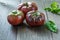 Fresh Black Brandywine Organic Tomatoes and basil on a wooden table.